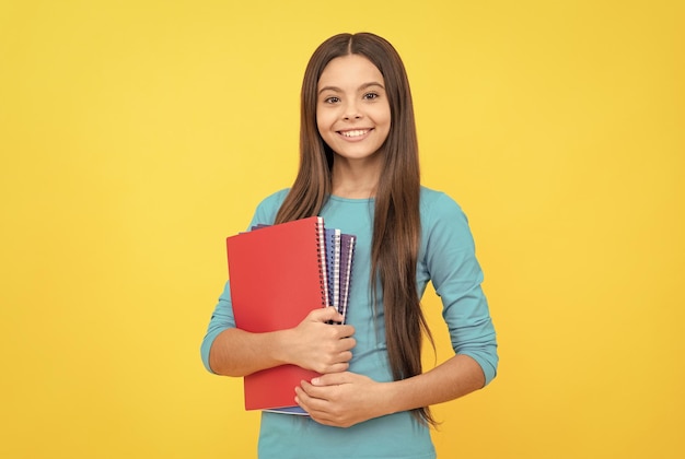 Une enfant joyeuse tient un bloc-notes pour l'étude des devoirs