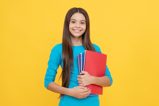 Une enfant joyeuse tient un bloc-notes pour l'étude des devoirs