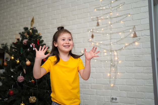 Un Enfant Joyeux Attrape Des Guirlandes. Des Vacances D'enfants Lumineuses. Un Enfant Vêtu D'un T-shirt Jaune Attrape Une Serpentine.