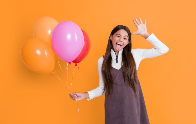 enfant joyeux avec des ballons d'hélium sur fond jaune
