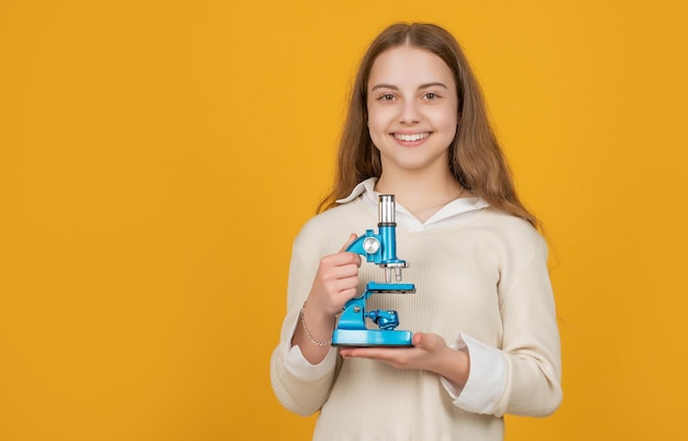 Enfant joyeux avec microscope sur fond jaune