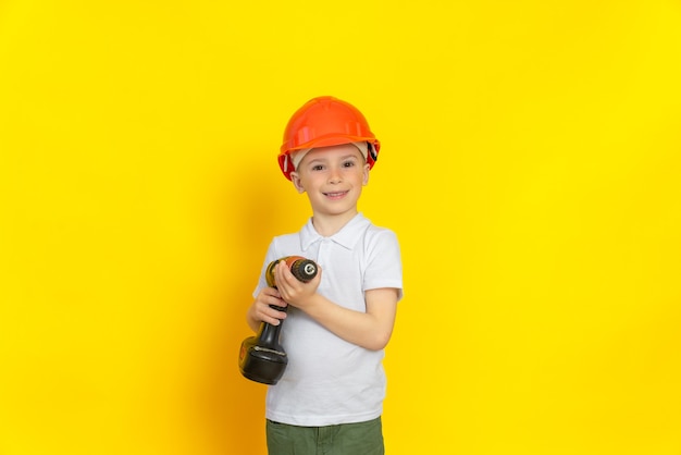 un enfant joyeux avec un tournevis dans les mains dans un casque sur la tête