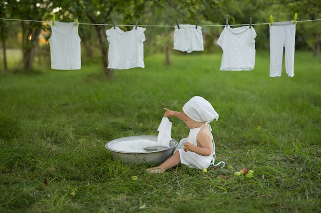 Un enfant lave gaiement ses vêtements dans le bassin, vaporisez de l'eau et de la mousse pour laver les vêtements.