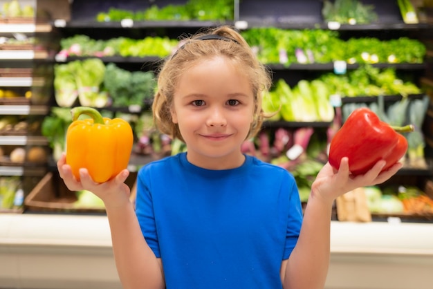 Enfant avec des légumes et des poivrons à l'épicerie L'enfant choisit des légumes et des fruits frais dans le magasin Enfant achetant de la nourriture dans un supermarché d'épicerie Acheter dans une épicerie