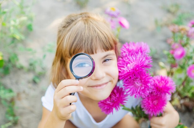 Enfant avec une loupe dans ses mains.