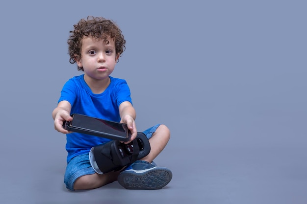 Enfant avec des lunettes de réalité virtuelle dans ses mains regardant curieusement comment ils fonctionnent