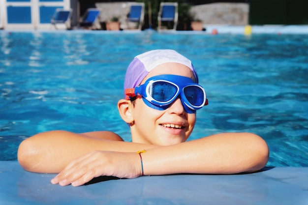 Enfant avec des lunettes souriant dans la piscine