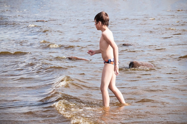 Enfant en maillot de bain marchant sur une mer peu profonde