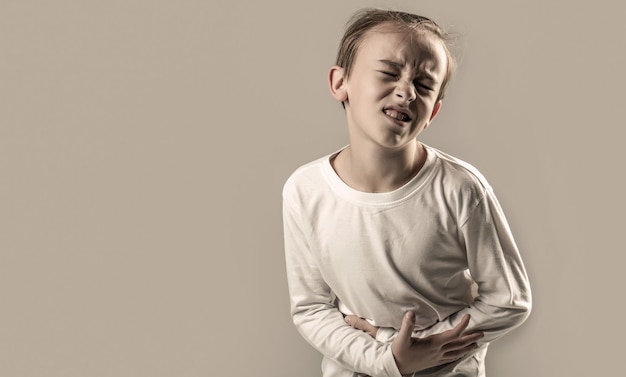 L'enfant a mal au ventre avec une intoxication alimentaire Enfant tenant les mains sur le ventre