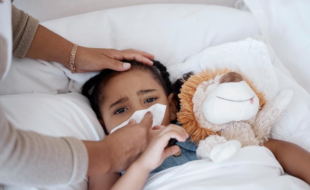 Enfant malade concerné mère et symptômes de covid au lit pour un problème de santé ou de la fièvre tout en s'essuyant le nez avec un mouchoir