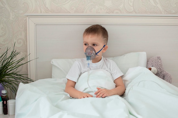 L'enfant malade est malade à la maison, allongé dans son lit avec un ours en peluche. Effectue la procédure d'inhalation avec un nébuliseur des voies respiratoires. traitement d'un enfant contre la toux. inhalateur compressif. Mise au point sélective.