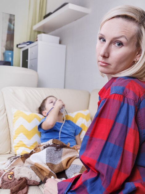 Enfant malade et mère. Enfant malade avec nébuliseur pédiatrique. Un petit enfant souffrant d'asthme ou de bronchite a du mal à respirer.