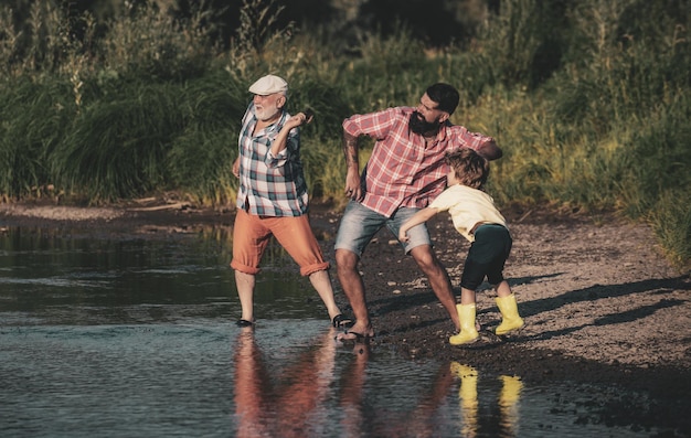 Enfant mâle avec père et grand-père sautant des pierres sur l'homme de l'eau à différents âges