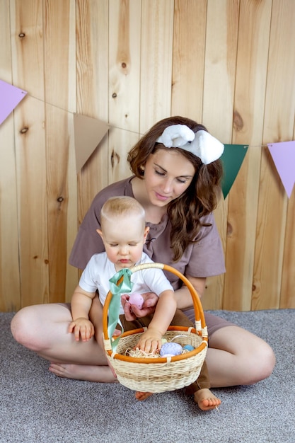 Enfant avec maman dans des oreilles de lapin s'asseoir en jouant avec des oeufs de Pâques Pâques