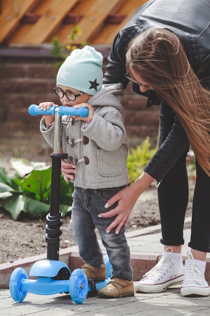 Enfant et maman jouent à l'extérieur avec des scooters.