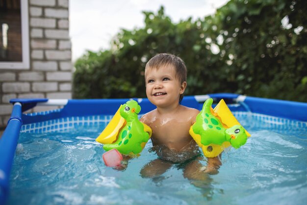 L'enfant en manches longues nage dans la piscine dans la cour