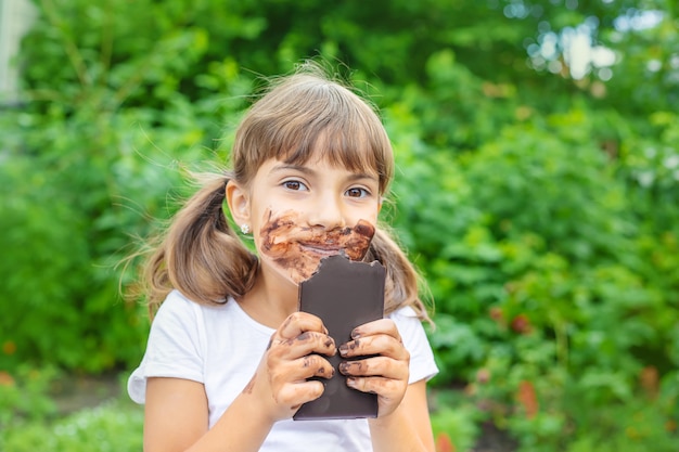 Photo l'enfant mange une barre de chocolat.