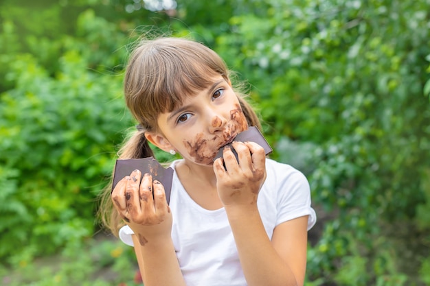 L'enfant mange une barre de chocolat.