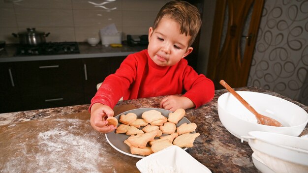 L'enfant mange des biscuits de Noël.