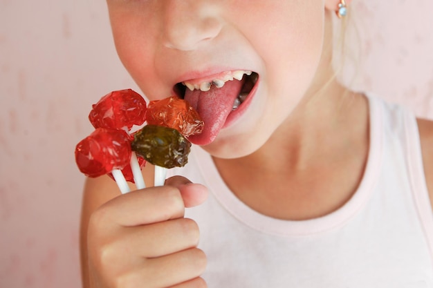 L'enfant mange des bonbons. La fille a des caries sur les dents.