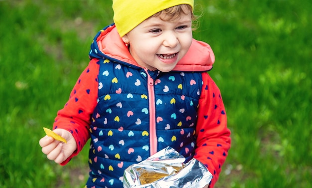 L'enfant mange des chips dans le parc Mise au point sélective