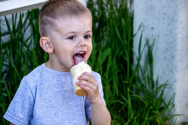 L'enfant mange de la crème glacée dans la nature, de la crème glacée dans une tasse. Nature. Mise au point sélective
