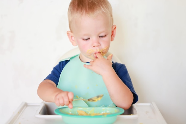 enfant mange avec une cuillère et apprend par lui-même