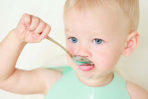 enfant mange avec une cuillère et apprend par lui-même