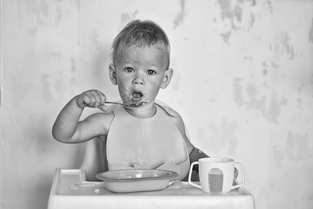 enfant mange avec une cuillère et apprend par lui-même