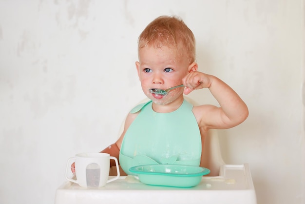 enfant mange avec une cuillère et apprend par lui-même