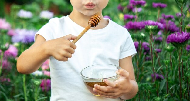 L'enfant mange du miel dans le jardin.