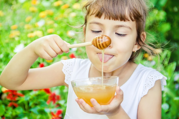 L&#39;enfant mange du miel. Mise au point sélective. nourriture nature