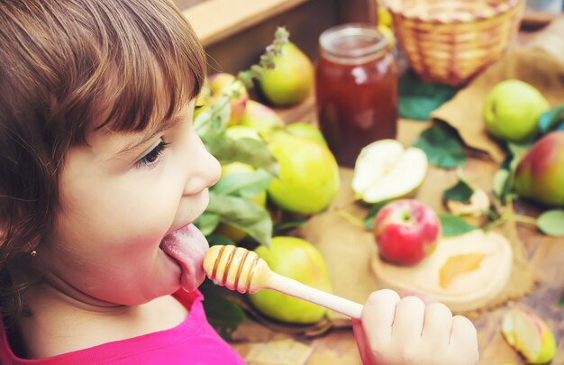 L&#39;enfant mange du miel et des pommes. Mise au point sélective.