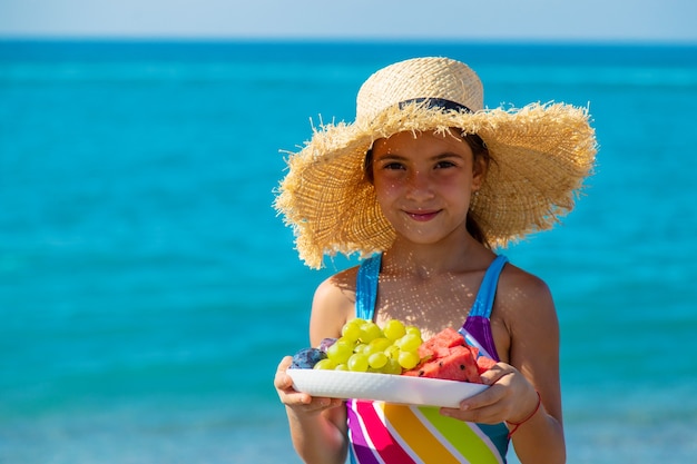 L'enfant mange des fruits au bord de la mer. Mise au point sélective.