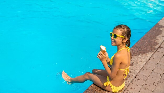 L'enfant mange une glace près de la piscine. Mise au point sélective. Enfant.