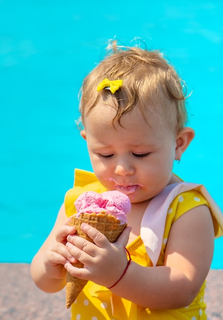 L'enfant mange une glace près de la piscine. Mise au point sélective. Enfant.