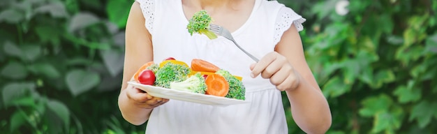 L&#39;enfant mange des légumes. Photo d&#39;été. Mise au point sélective