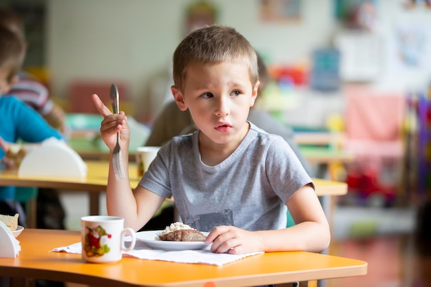 Un enfant mange à la maternelle