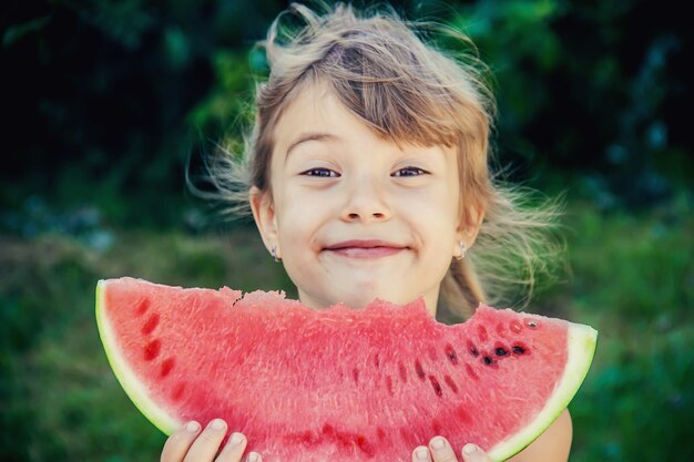 L'enfant mange de la pastèque en été. Mise au point sélective.