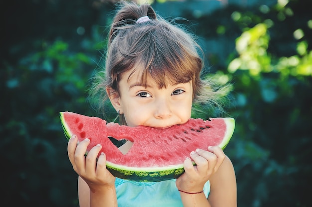 L'enfant mange de la pastèque en été. Mise au point sélective.