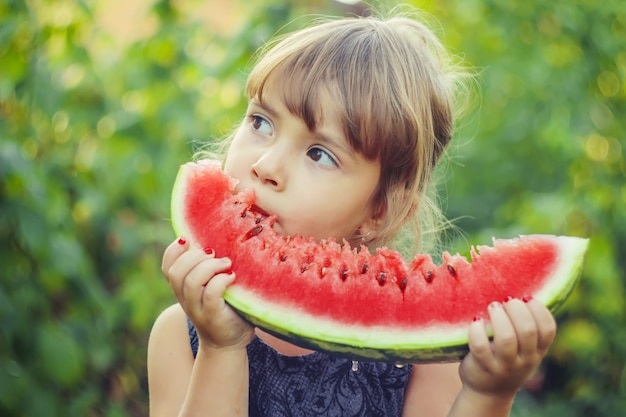 Un enfant mange de la pastèque. Mise au point sélective. la nature.