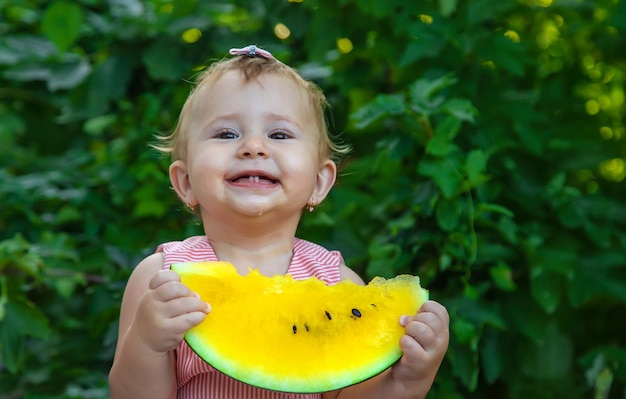 L'enfant mange une pastèque. Mise au point sélective.