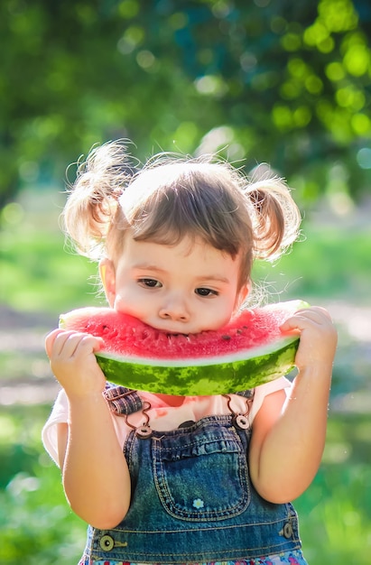 Un enfant mange de la pastèque. Mise au point sélective.