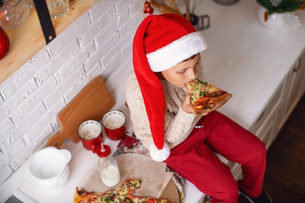 un enfant mange de la pizza dans la cuisine