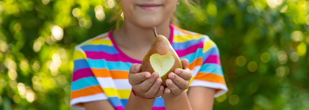 L'enfant mange une poire dans le jardin. Mise au point sélective. Enfant.