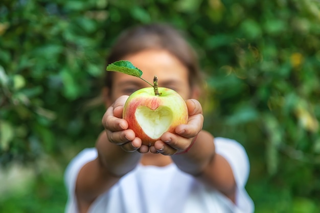 L'enfant mange une pomme dans le jardin. Mise au point sélective. Enfant.