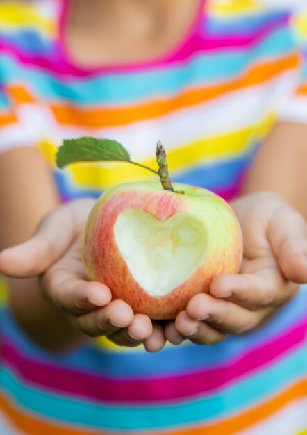 L'enfant mange une pomme dans le jardin. Mise au point sélective. Enfant.