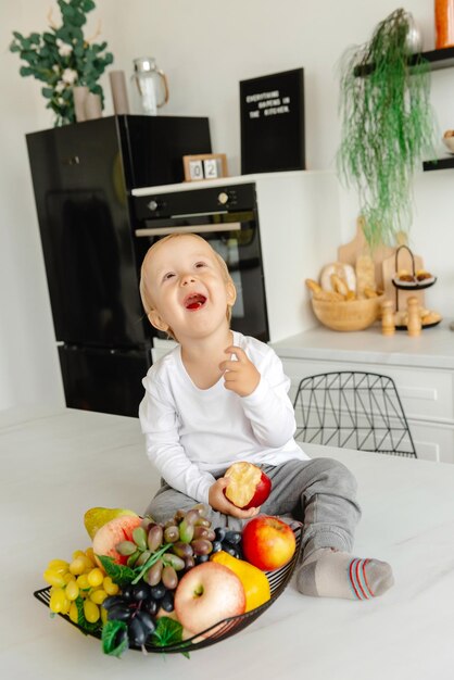 L'enfant mange une pomme pour le petit déjeuner assis dans la cuisine une alimentation saine pour toute la famille rouge