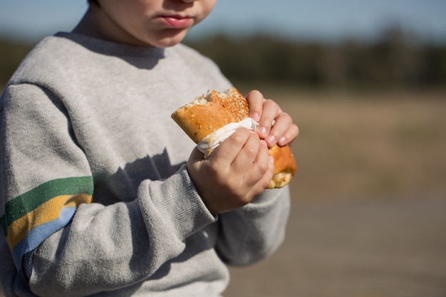 L'enfant mange un sandwich en plein air