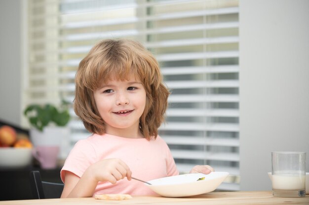 Enfant mangeant des aliments sains mignon petit garçon ayant de la soupe pour le déjeuner